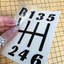 A black version of the 6 Speed decal being held with part of the transfer tape layer lifted away from the backing. This image illustrates how the graphic has no background and can be installed using the transfer tape to keep everything in place. Once installed, the transfer tape can then be removed, leaving only the graphic itself behind. thumbnail